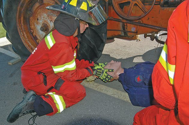 Carissa Teichroeb, a firefighter with the Longview, Alta., division of the Foothills Fire Department, supports the head of a mock victim of a tractor accident. | Barb Glen photo