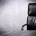 A boardroom-style chair sits empty in front of a table.