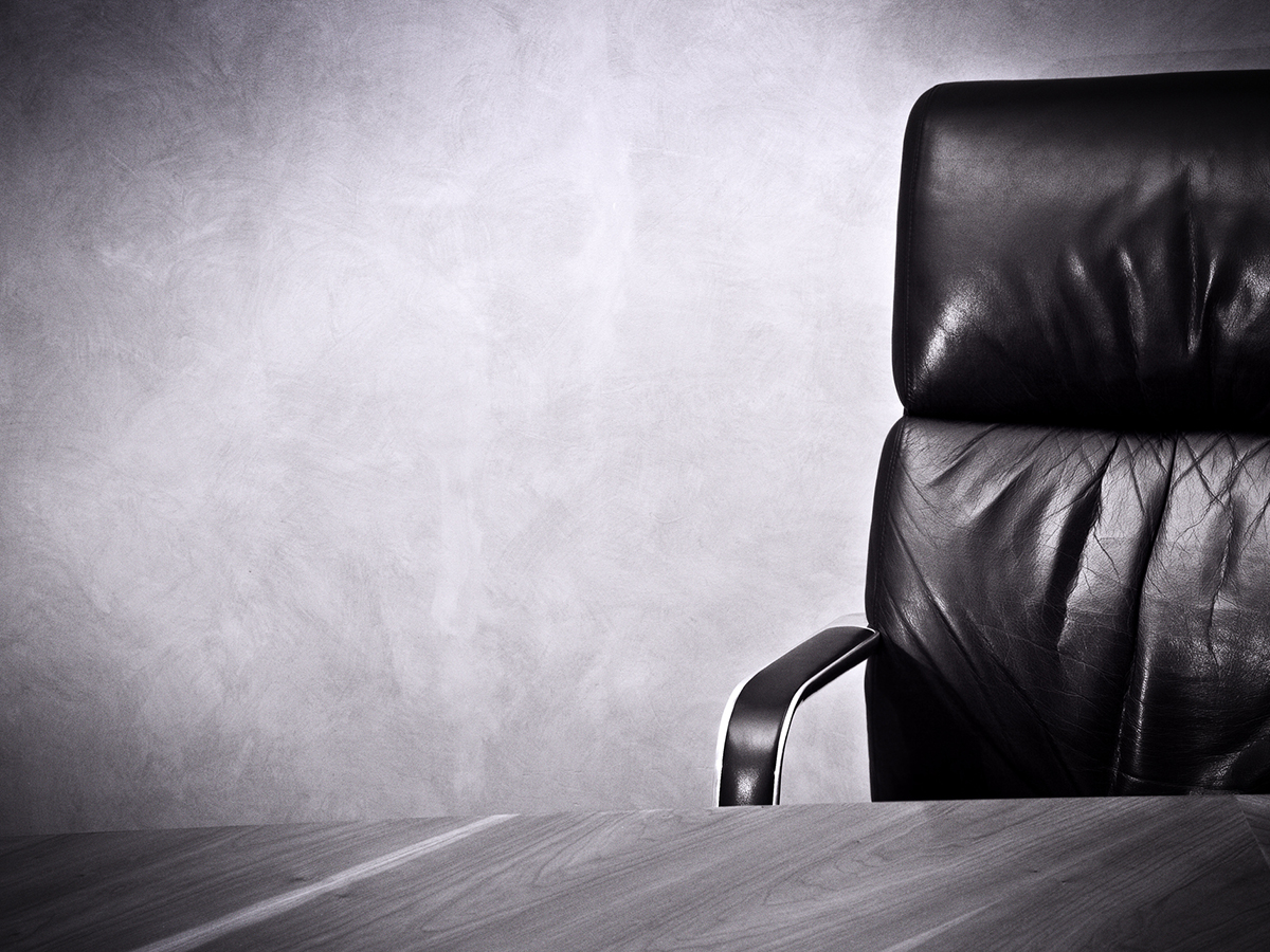 A boardroom-style chair sits empty in front of a table.
