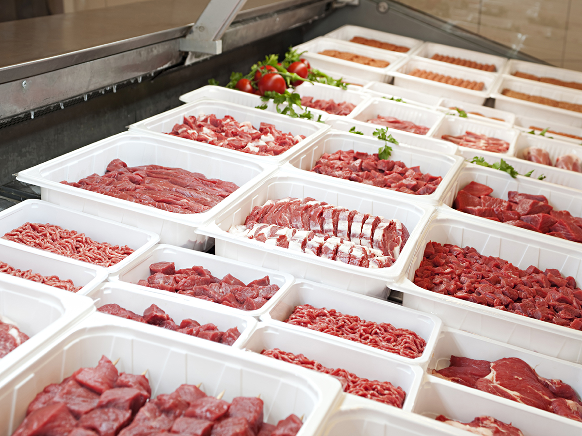 Various cuts of raw red meat are on display in a meat shop.