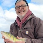 Bill Nitzsche smiles while holding a master angler perch taken when ice fishing on Shoal Lake.