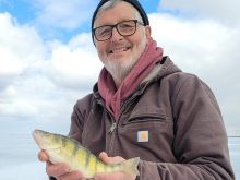 Bill Nitzsche smiles while holding a master angler perch taken when ice fishing on Shoal Lake.