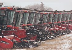 A row of new red combines sit in a field.