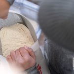 An overhead shot of someone scooping flour out of a paper bag.