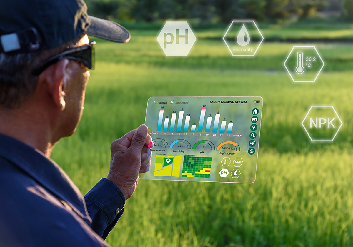 A farmer holds a clear, futuristic tablet-like device with weather and crop data information on it and above it.