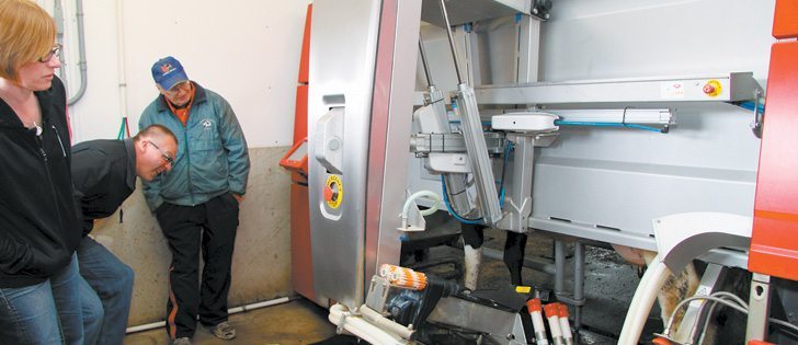 Garth Hockley, right, installed a milking robot on his dairy farm near Brandon 17 months ago, but the novelty hasn’t worn off. Hockley still enjoys showing the technology to visitors, such as Jennifer and Harley Strudwick of Balgonie, Sask.  |  Robert Arnason photo