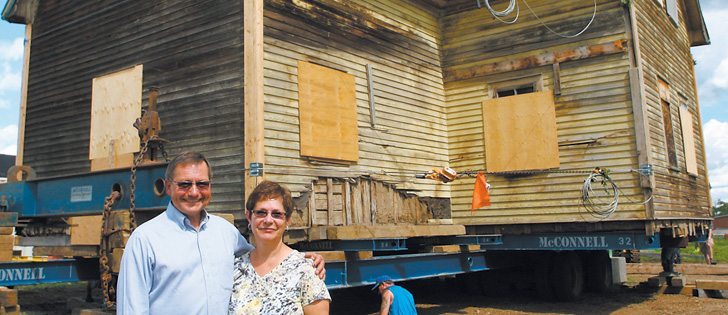 Former Alberta premier and  agriculture minister Ed Stelmach and his wife, Marie, stand in front of the house built by his grandparents, Nykola and Theodora Stelmach, who immigrated to Canada from Ukraine in 1898. The log house was built in 1915. On August 1, it was moved 50 kilometres from Stelmach's farm near Andrew to the Ukrainian Cultural Heritage Village, east of Edmonton. | Mary MacArthur photo