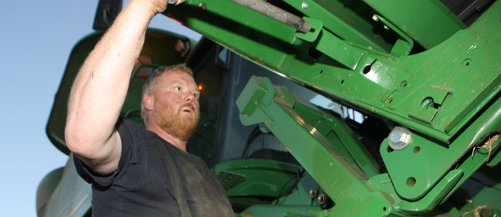 Richard Germain of Rolla, B.C., slides a pin in place as he hooks up the header to a combine for Borek Farms of Dawson Creek, B.C. Yields are disappointing in these fields, following a dry summer, but across the Prairies the wheat harvest looks strong, especially for those farmers who applied fungicides.  |  Mary MacArthur Photo