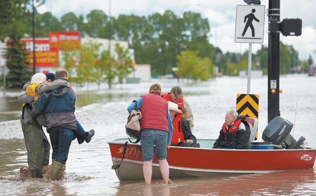  A woman is rescued by boat in High River, Alta. A state of emergency was declared in the town and residents were evacuated.  |  Mike Sturk photo