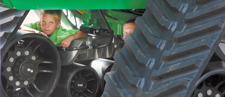 Dennis, left, and Wilco Dewinter of Lucky Lake, Sask., found a $165,000 play structure, not including the $450,000 tractor, while attending Regina’s Canada’s Farm Progress Show June 21. The pair discovered the Soucy track system for the new 9R John Deere four wheel drive tractor made an excellent form of entertainment while their father talked machinery with other farmers.  |  Michael Raine photo