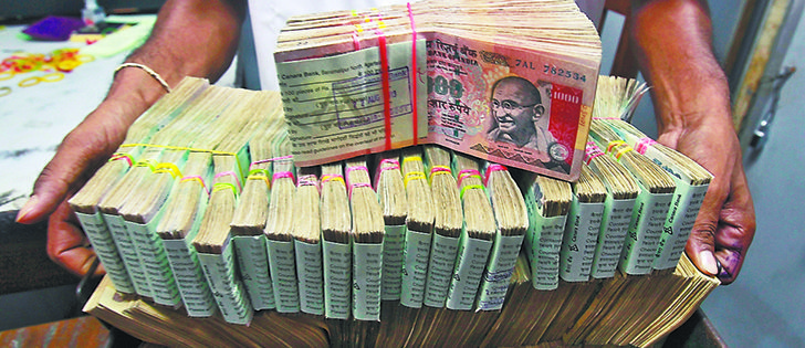 An employee poses with the bundles of Indian rupee notes inside a bank in Agartala in northeastern India Aug. 22. The Indian rupee fell past 65 to the dollar to a record low Aug. 26, after Federal Reserve minutes hinted that the U.S. was on course to begin tapering stimulus as early as next month and as foreign investors become sellers of Indian stocks. |  REUTERS/Jayanta photo