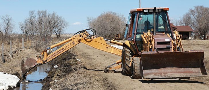 A backhoe operator clears a drainage ditch west of Warman, Saskatchewan, on May 4, 2013.
