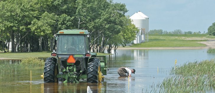 Doug Schofer of Melville, Sask., searches for sandbags that fell off his tractor’s bucket. The road into his farm was flooded but luckily his house, barns and bins were safe. Residents of eastern Saskatchewan and Manitoba scrambled to protect themselves and their belongings from floods last week. Although the water has receded for many, cleanup continues.  |  William DeKay photo
