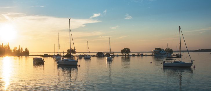 The setting sun highlights boats on Clear Lake in Manitoba’s Riding Mountain National Park. |  Arlene and Robin Karpan photo