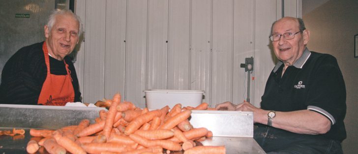 Walter Lietz, left, and Ernie Murschel wash carrots and remove any blemishes as they volunteer at Prairie Gleaners. | Barb Glen photo