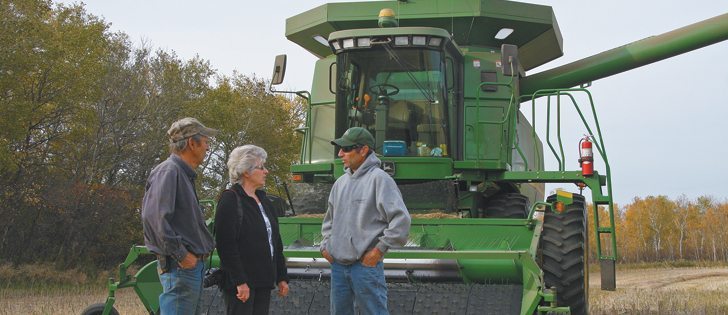 Les, left, Elsie and Kenton Hunter stand in their recently harvested field of canola while taking a break after a long day spent in the combine. | Ashley Robinson photo