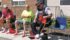 Bryan Romaniuk, left, and Mario Caron watch as Consort, Alta., RCMP Const. Jim Countryman puts on red high heels. They were participating in the Walk a Mile in Her Shoes event to increase awareness of violence against women and raise funds to support victims. | Karen Morrison photo