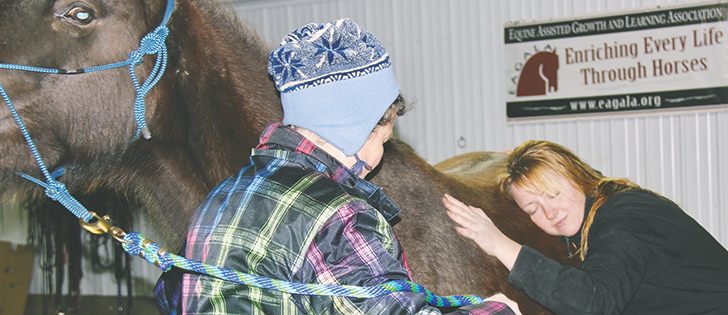 Amber Magnusson, left, receives coaching from Nancy Maurer about how to lean into a horse to relax and hear its heart beat. | Christalee Froese photo