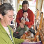 Nancy Warwaruk weaves on one of her Leclerc looms. She uses 100 percent cotton thread to make a piece of fabric that will result in 24 tea towels. Weave time is 30 to 45 minutes per towel. Looking on are
husband Corwyn and son Chance. | Maria Johnson photo