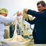 Skeena Ngo, a research and development assistant at Crust Craft, and Alberta Agriculture Minister Oneil Carlier transfer dough to a mixer. Crust Craft has taken part in the government’s energy efficiency grant program. | Jeremy Simes photo
