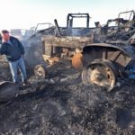 Mark Wiebe talks to a neighbour while walking through the charred remains of his machine shop that fire destroyed March 19. The Osler, Sask., dairy farmer lost his sprayer, semi-tractor and super B trailer, feed wagon and feed truck, several tractors including a restored vintage tractor. | William DeKay photo