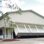 Hydraulic doors offer large capacity lifting and stability for sheds and shops. This door got a creative touch with an added porch, windows and man door. Chairs and even plants lift along with the unit. | Schweiss doors photo