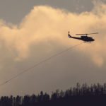 A helicopter with a water bucket flies over a wildfire in British Columbia during the summer of 2017. Grazing is going to be delayed this year in much of the province because of the fires. | REUTERS/Ben Nelms photo