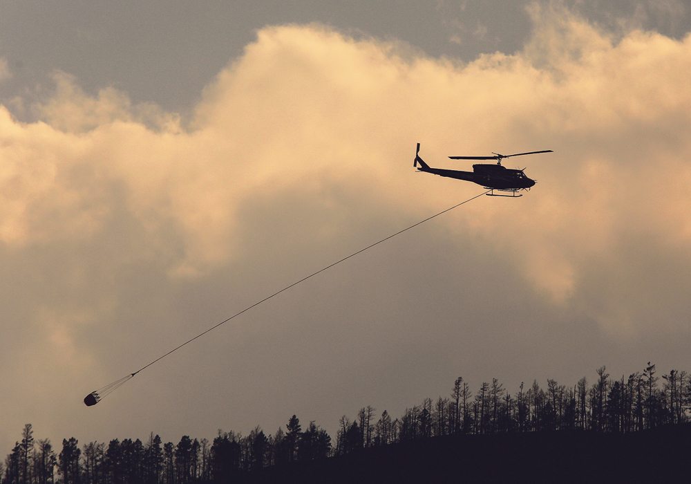 A helicopter with a water bucket flies over a wildfire in British Columbia during the summer of 2017. Grazing is going to be delayed this year in much of the province because of the fires.  |  REUTERS/Ben Nelms photo