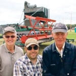 Volunteers Jake Hamm, left, Nathan Sims and Helmut Neufeld have brought a 1929 Massey Harris 9B combine back to life after much work. | Ed White photo