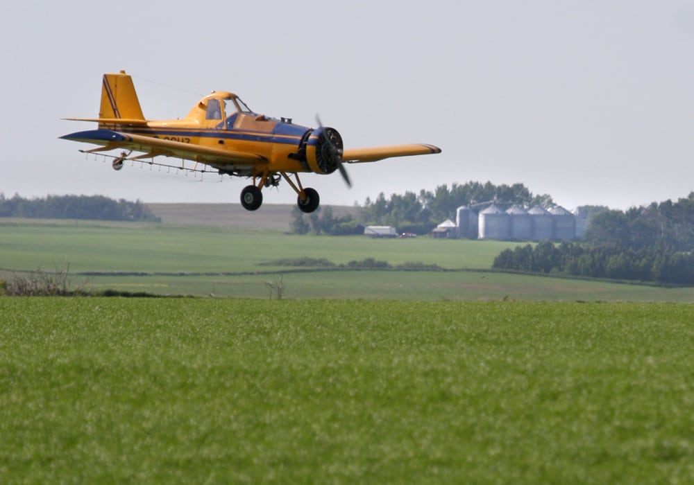 A Westlock, Alta., aerial-spraying company faces four charges for alleged failure to comply with regulations. This photo of a spray plane at work was taken in 2007. | File photo