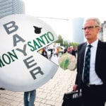 A shareholder arrives at Bayer’s annual general meeting in Bonn, Germany, May 25 as people protest against the merger of the pharmaceutical and chemical maker with U.S. seeds and agrochemicals company Monsanto. A recent court ruling that it inherited from Monsanto has slashed Bayer’s share value. | REUTERS/Wolfgang Rattay photo