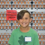 Emerson Tabelon and his family entered a contest and won a visit to a working egg farm. Here, he poses with flats of eggs collected at the Brant Hutterite Colony egg operation. | Barb Glen photo