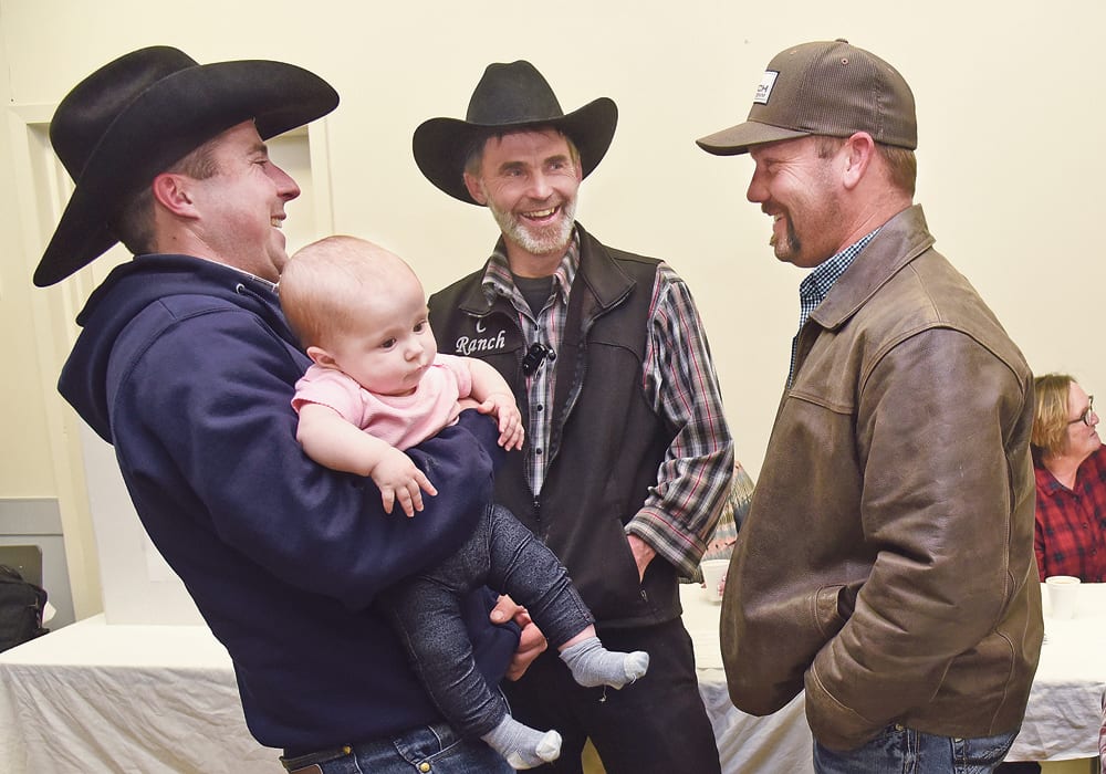 Garret Poletz holds six-month-old daughter Houstyn while talking with Ike Wipf and Joel Kampen during the Saskatchewan Cattlemen’s Association district 7 meeting in Kindersley Oct. 22.  |  William DeKay photo