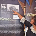 Deborah Dobbin points out an archival photo of her grandfather working on a threshing crew. The photo was part of a display about the award-winning documentary film that Dobbins helped create, documenting black settlers in Alberta and Saskatchewan. | Barb Glen photo