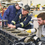 Grade 11 student Jaxon McIvor, left, of Eston High School, watches apprentice students Royce Knight and Thomas King begin to install sleeves on an Iveco 13 litre, six cylinder engine during an agriculture equipment technician boot camp at Saskatchewan Polytechnic Nov. 29. | William DeKay photo