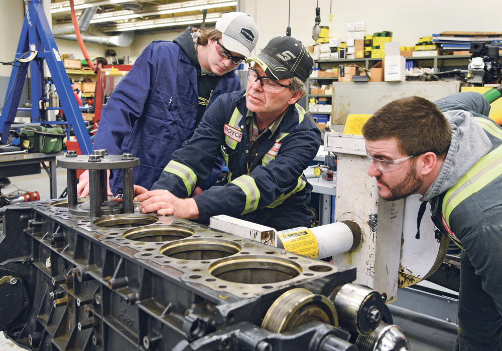 Grade 11 student Jaxon McIvor, left, of Eston High School, watches apprentice students Royce Knight and Thomas King begin to install sleeves on an Iveco 13 litre, six cylinder engine during an agriculture equipment technician boot camp at Saskatchewan Polytechnic Nov. 29.  |  William DeKay photo