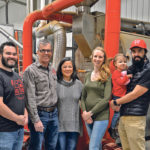 The Hamill family, which run Red Shed Malting on their farm near Penhold, Alta., now includes three generations: Matt, left, John, Susie, Daelyn, Joe and two-year-old Isabella. They are standing in front of the company’s malt roaster. | Maria Johnson photo