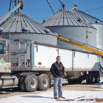 Soybean farmer Austin Rincker poses for a photograph near a grain truck and storage bins on his farm near Moweaqua, Illinois, earlier this month. Rincker will farm approximately 2500 acres in the upcoming season, split evenly between corn and soybeans. Young farmers in the United States are feeling the financial pinch of years of low commodity prices. | REUTERS/Daniel Acker photo