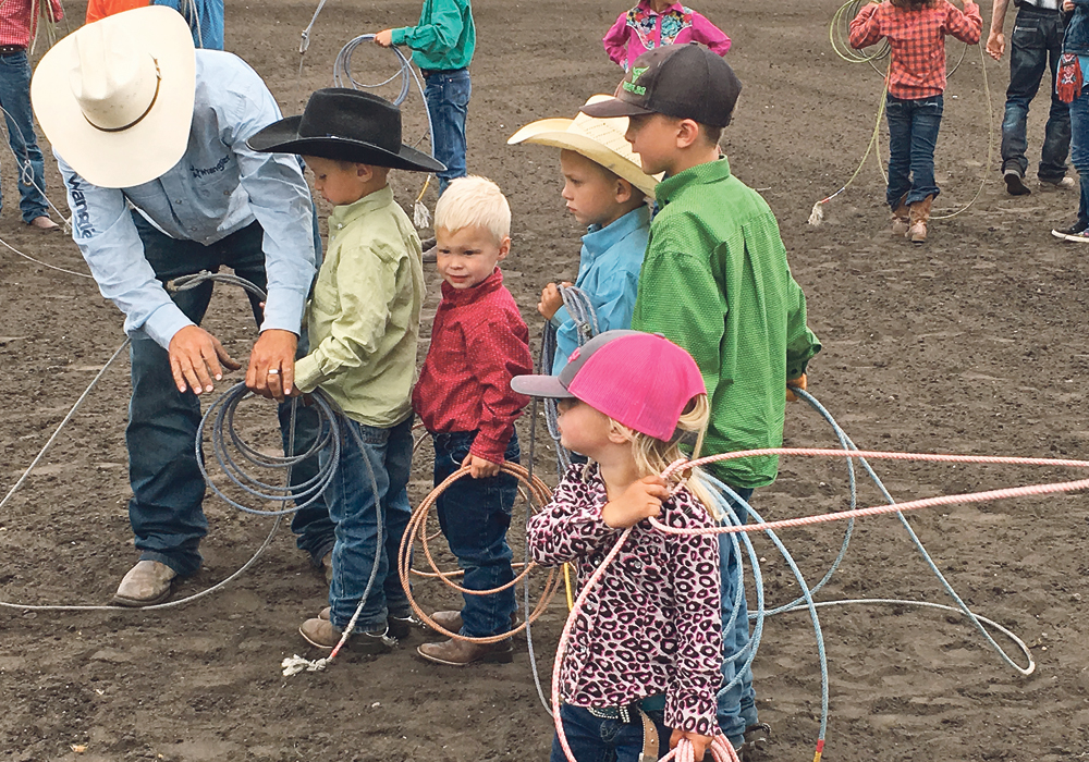 Shane Brown helps his son, Slone, with his loop during the dummy roping event at last year’s event while Slone’s brother, Brock, and cousins Kesler and Carter Brown wait their turn. Sister Dally in the foreground.  |  Kelly McIntyre photo