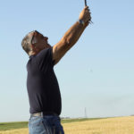 Robert Whyte, a vice-president with Ventura Foods, stretches to get the optimal photo of a wheat field near Winnipeg.  |  Robert Arnason photo