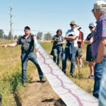 Invasive weed specialist Kelley Cooley has a visual aid to show just how long the roots of leafy spurge can be. He spoke about invasive weeds and their control at a July 25 Farming Smarter field event. | Barb Glen photo
