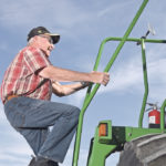 Stairway to harvest: Herman Kirstein of Raymore, Sask., climbs the ladder on his John Deere 9750 with a 35-foot MacDon header. | William DeKay photo