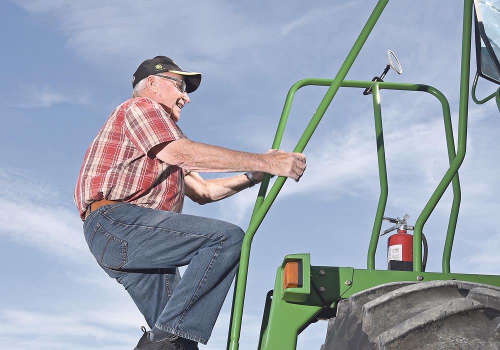 Stairway to harvest: Herman Kirstein of Raymore, Sask., climbs the ladder on his John Deere 9750 with a 35-foot MacDon header.  |  William DeKay photo