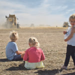 Jordana Slingerland, right, checks her surroundings while her brother and sister, Denver and Kadence, watch as combines harvest a crop for the Canadian Foodgrains Bank Aug. 29. | Barb Glen photo