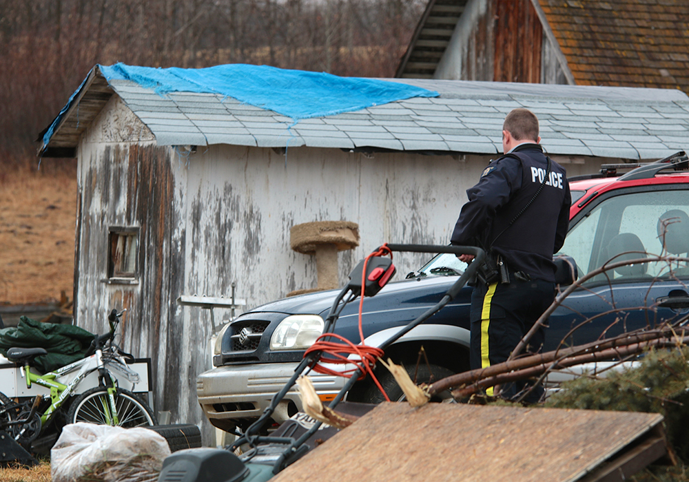 An RCMP officer examines a rural property in the St. Paul, Alta. area.  |  Jeremy Simes photo