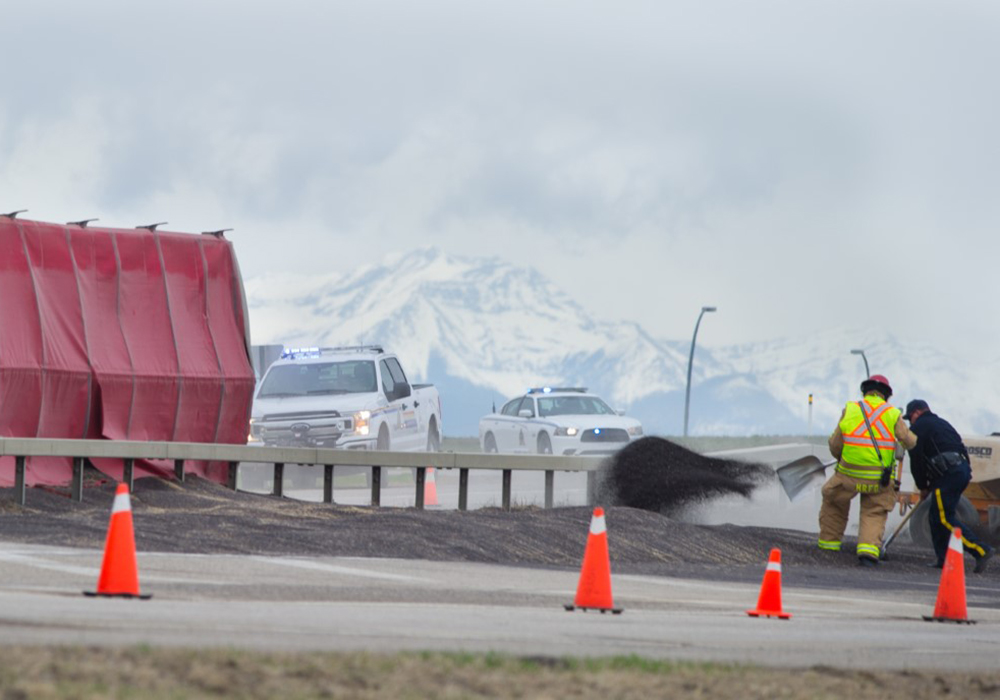 Fire crews and police clean up canola spilled onto Hwy 23 just east of the High River overpass Monday. | Mike Sturk photo
