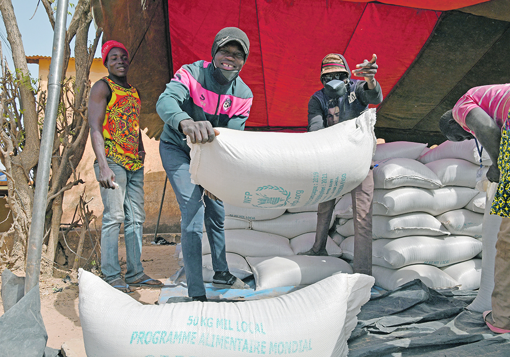 Workers carry aid provided by the World Food Program for distribution in Pissila, Burkina Faso, in January.  |  Reuters/Anne Mimault photo