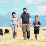 The Rocky Mountains rise up in the distance as Hugh McLuckie, left, and Hadley, Logan, Edric and Lynette Van Steinburg walk through Saint Mary’s Prairie with four of the nine Border Collies they raise. | Christalee Froese photo