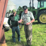 Mel Paton, left, visits with former employee Ernie Hansen as they unload a truck of wheat into the bin on the first day of harvest. |Curt Paton photo