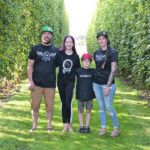 Colin, left, Maya, Aspen and Jaclyn Smith stand in the cool shaded space between rows of hops. Each plant is strung from a trellis system made using 19 foot T-shaped steel poles. These poles are unique because most hop growers around the world use a traditional wood system. | Maria Johnson photo